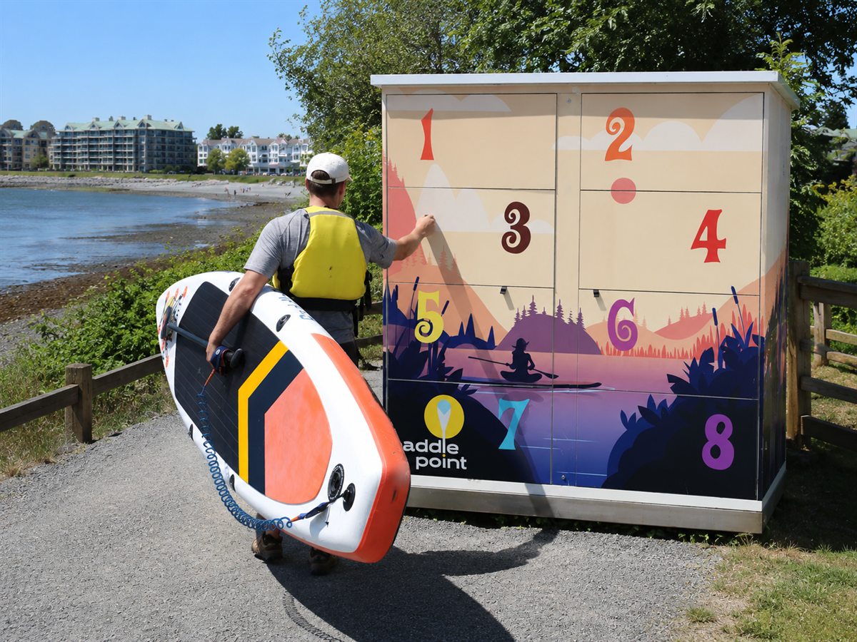 Paddler carrying a paddleboard away from the Parksville locker