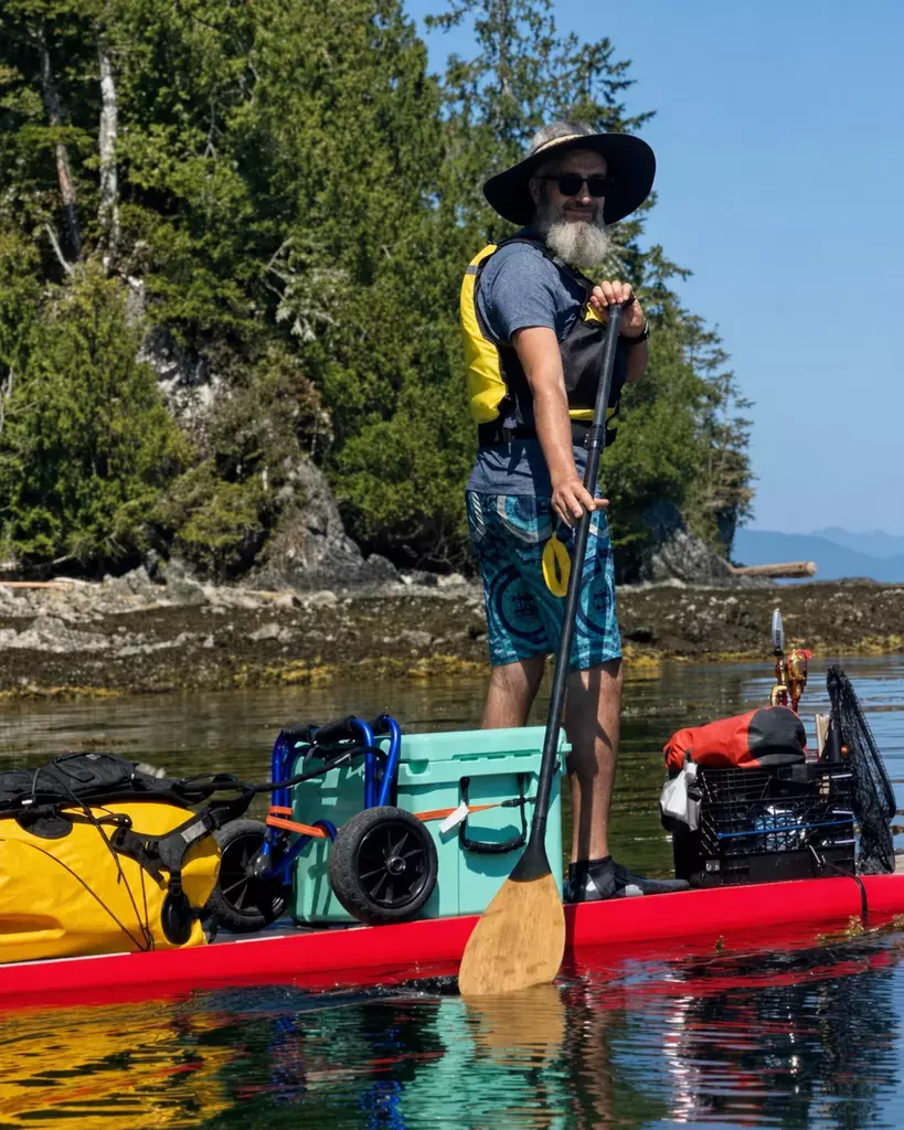 Adil Bahi paddling beside a forested Vancouver Island shoreline.
